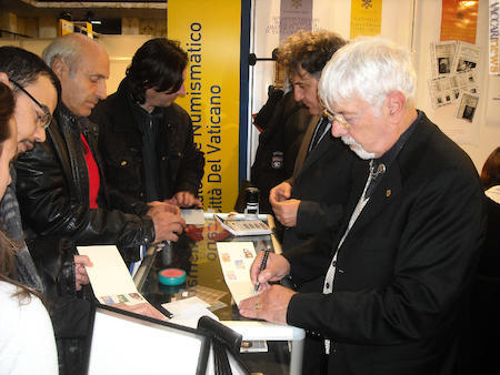 Giorgio Borghesani, in primo piano a destra, presso lo stand dell’Ufficio filatelico e numismatico vaticano; era l’edizione 2011 di “Romafil”. Stava firmando l’emissione dedicata ai viaggi del papa