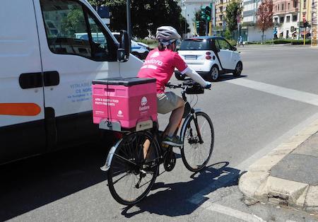 Con bicicletta, casco e contenitore termico alla consegna: una fattorina di Foodora