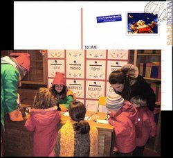 L’ufficio postale di Babbo Natale organizzato da Poste italiane: una delle cartoline con tanto di «francobollo» ed «annullo» già applicati e, sotto, i bambini intenti a compilarle