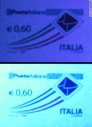 I due francobolli a confronto sotto la lampada ad ultravioletti: l'esemplare normale e, sotto, quello su carta siliconata